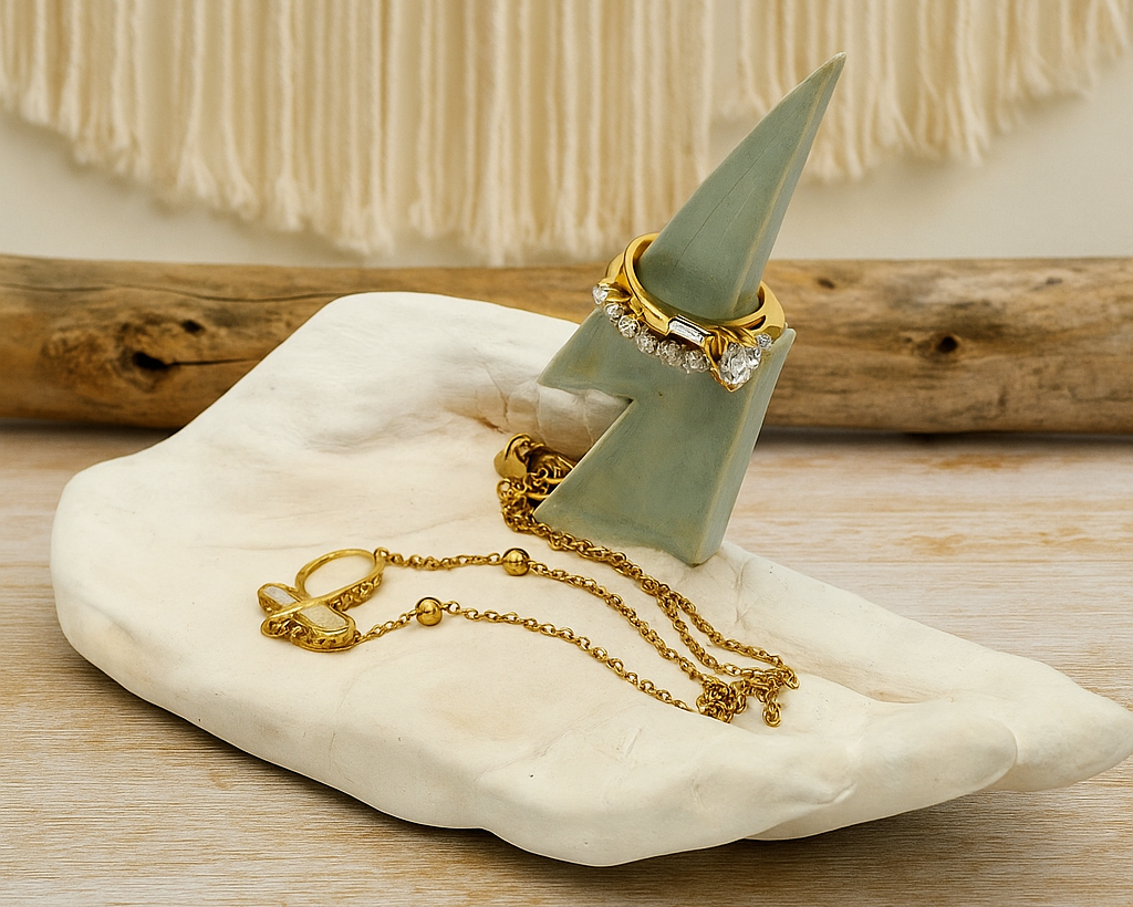Jewelry holder in the shape of a hand with a lightning bolt coming out of the palm. Made of ceramic. The image shows a ring and a necklace displayed on the product in a decorative background.